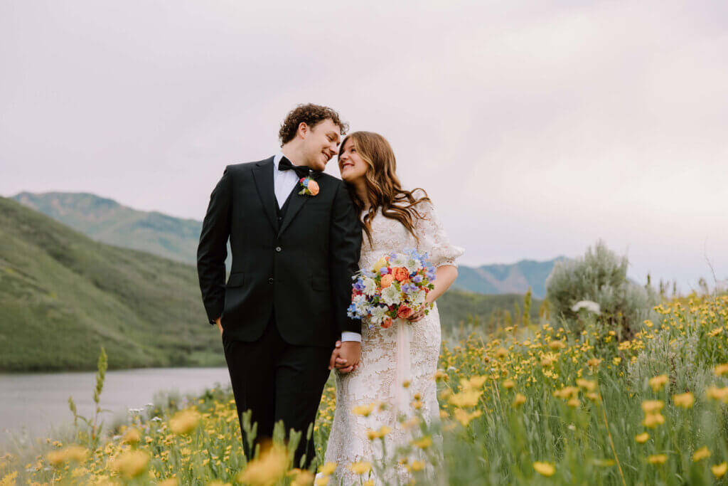 bride and groom holding hands in flower field